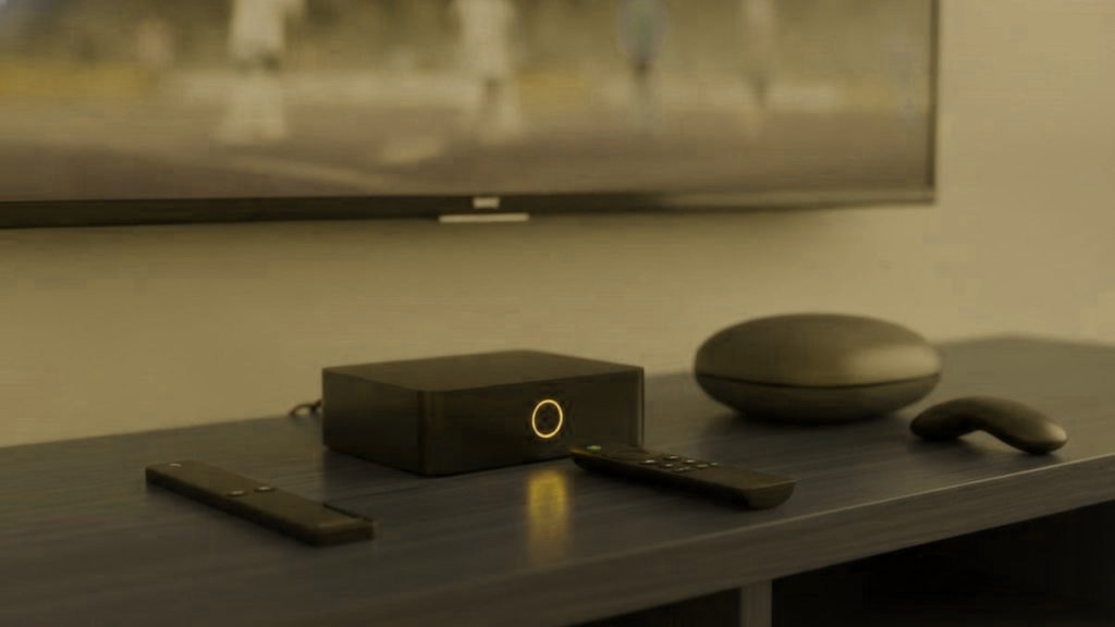 A streaming stick, a set-top box and a streaming box with remotes on a TV console for IPTV