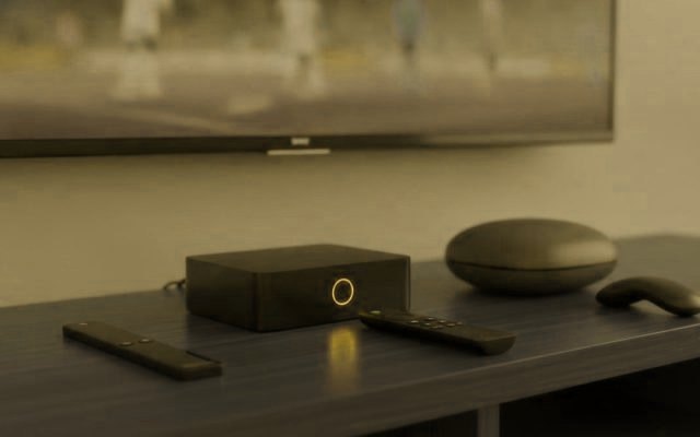 A streaming stick, a set-top box and a streaming box with remotes on a TV console for IPTV